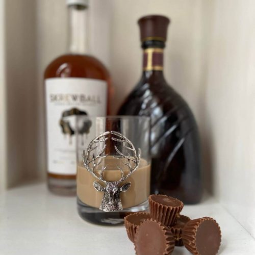 Reeses peanut butter in a cup cocktail with mini reeses pb cups, peanut butter whiskey bottle, and chocolate liqueur bottle