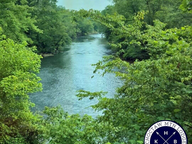 Toccoa Rive surrounded by trees with KHB Vacation Rentals Choctaw Mountain Lodge logo in the corner